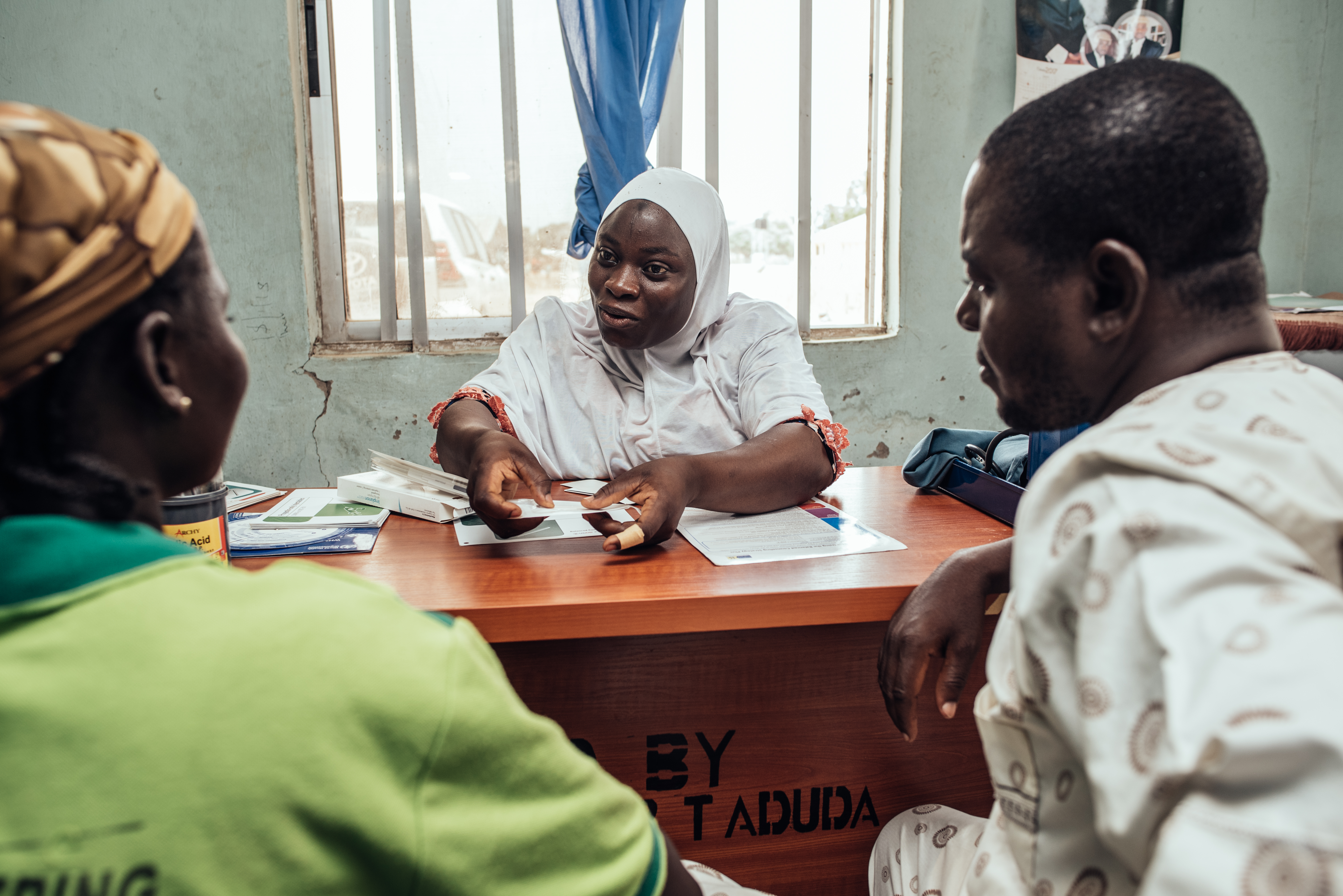 A health provider sits a desk infront of a couple.
