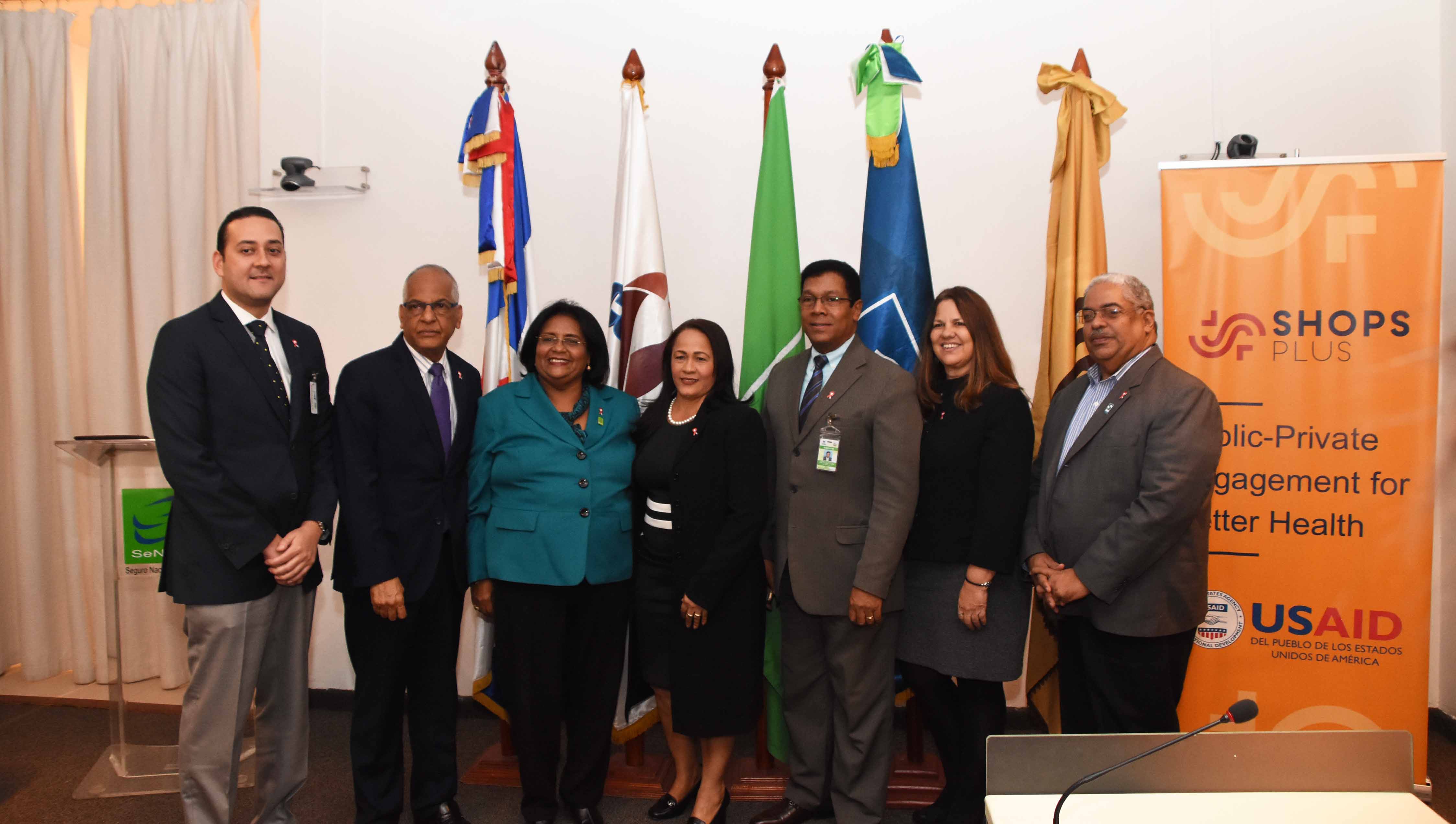Representatives from SHOPS Plus, USAID, and the other organizations at a signing ceremony in the Dominican Republic. A SHOPS Plus banner stands behind the group.