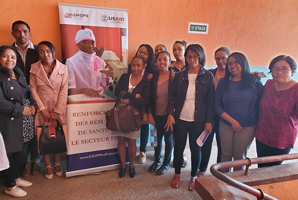 Group photo of participants in front of a SHOPS Plus banner