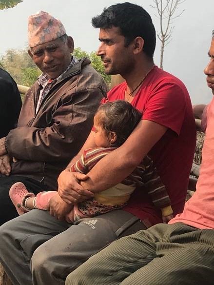 A man holding his young child while listening to a discussion