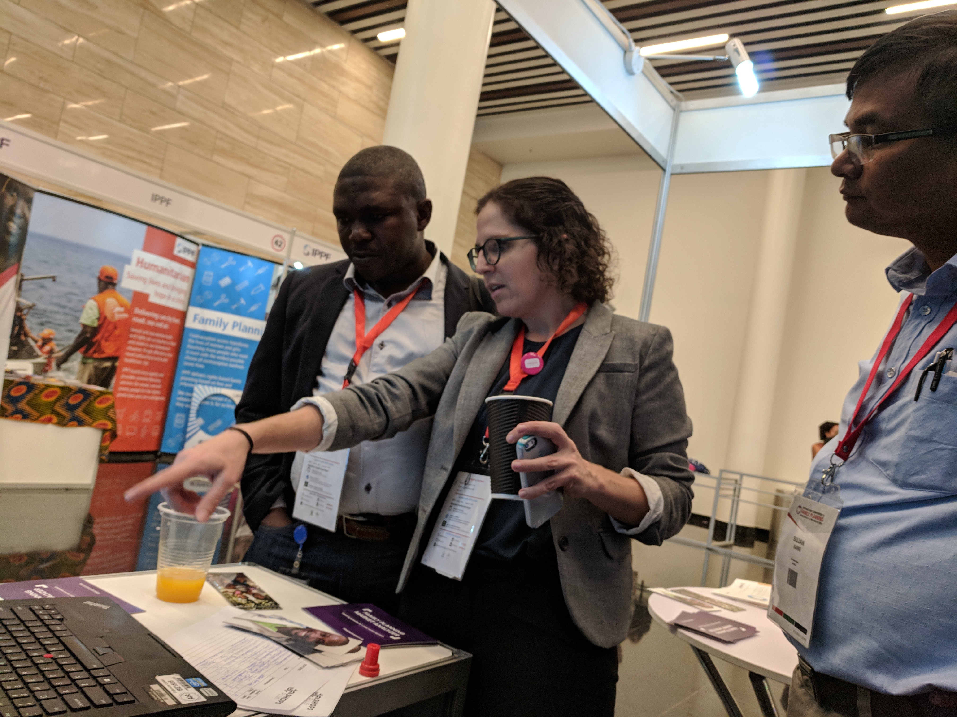 Michelle Weinberger demonstrating the tool on a laptop to onlookers at the SHOPS Plus booth at ICFP.
