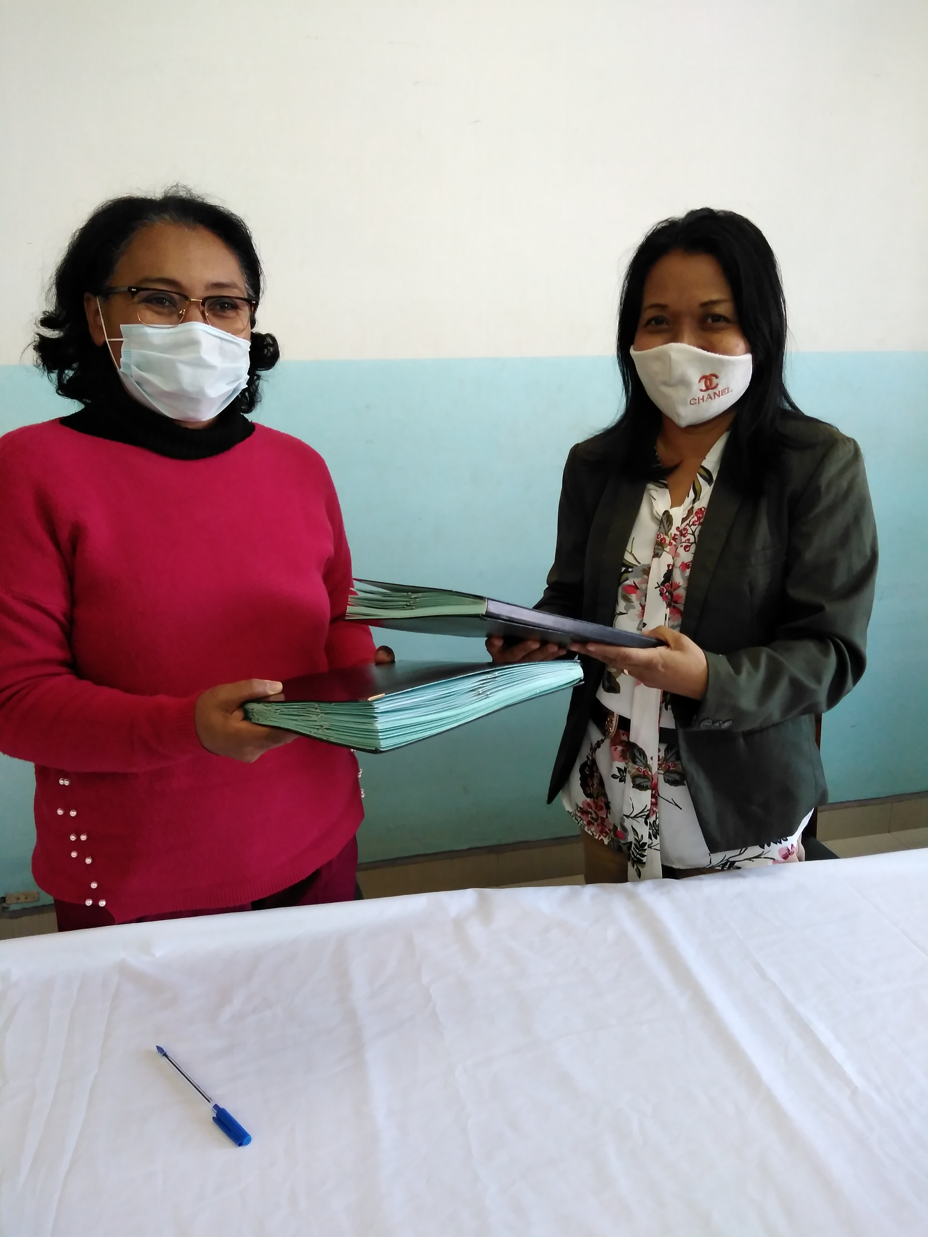 Two women handing over signed MOU documents
