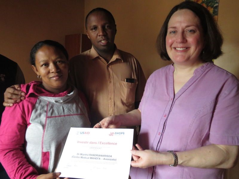 Stephanie Gober, SHOPS Plus access to finance specialist, presents the “Investing in Excellence” certificate to Dr. Miantra Randrianarison, her husband Dr. Serge Mahefa Rakotozafy.