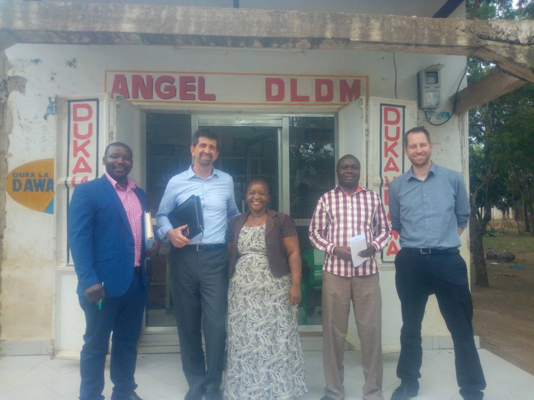 Mariam standing in front of her drug shop with SHOPS Plus staff