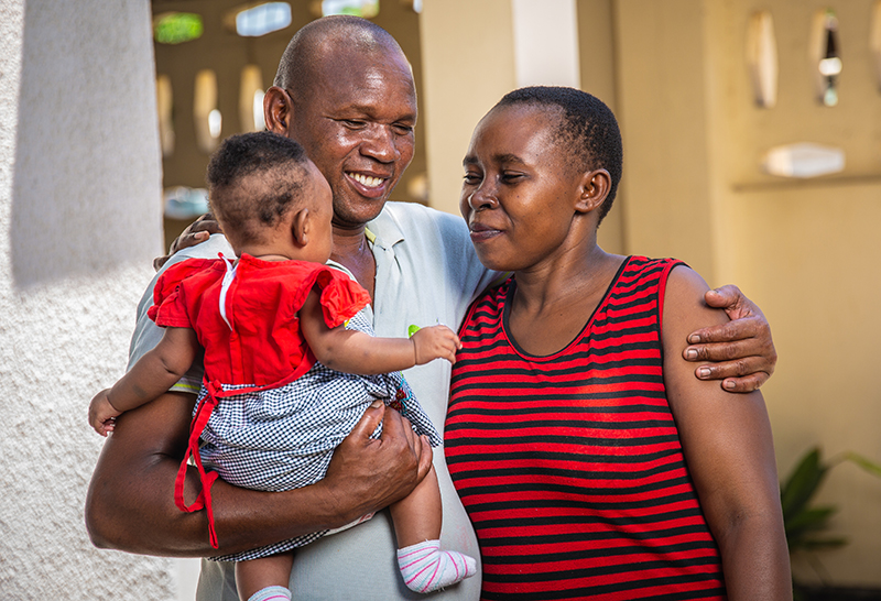 Tanzanian mom, dad, and baby hugging