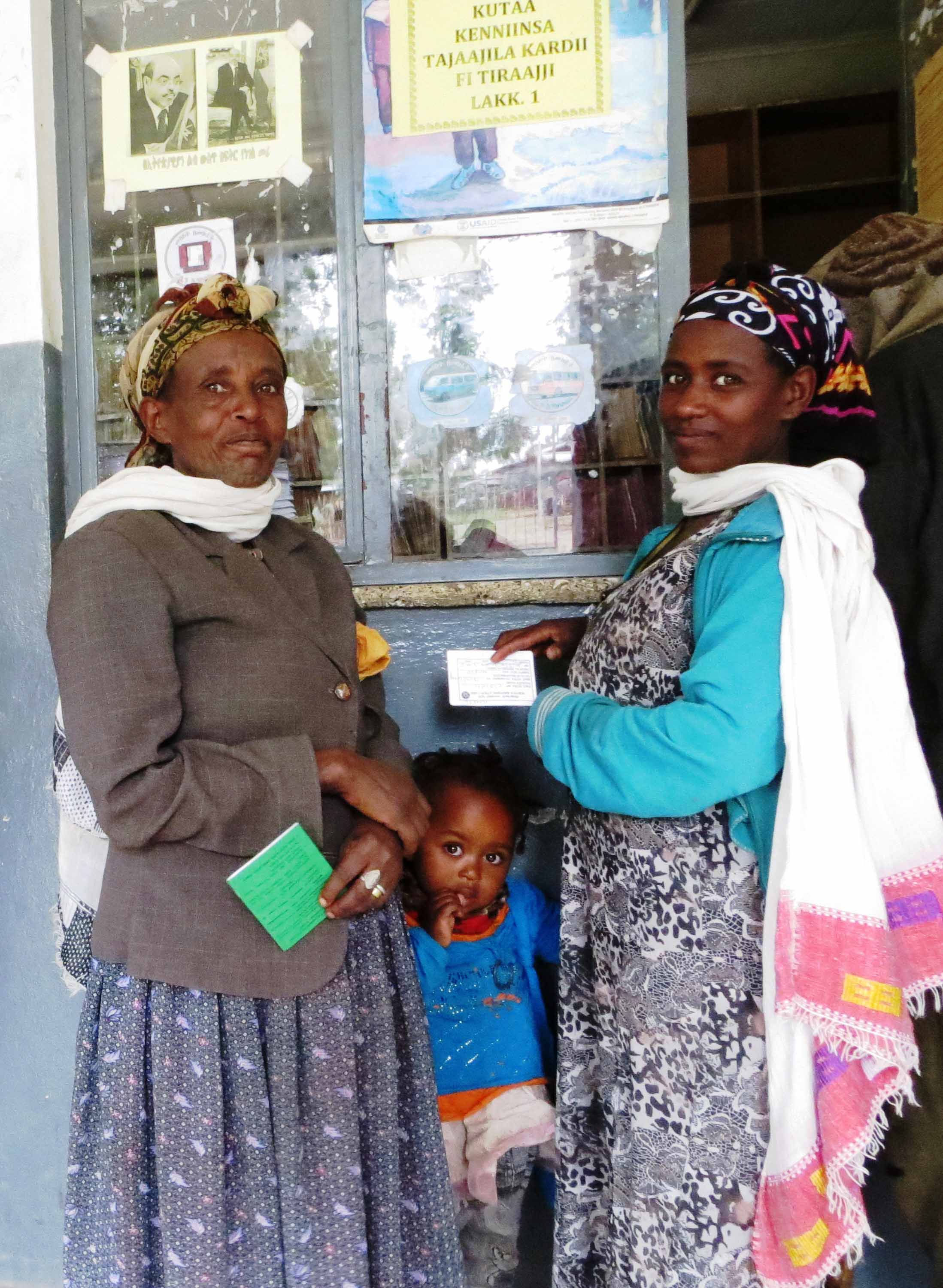 Two women standing with a child outside a shop.