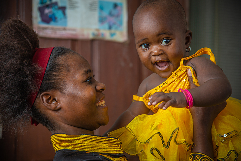 Mom holding her baby, both are smiling.